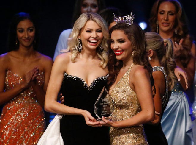 Miss Gainesville Halle Burton receives the second runner-up trophy from 2023 Miss Florida Juliette Valle before the final name is announced at the 2024 Miss Florida Pageant Finals at the RP Funding Center in Lakeland on Saturday June 29, 2024.